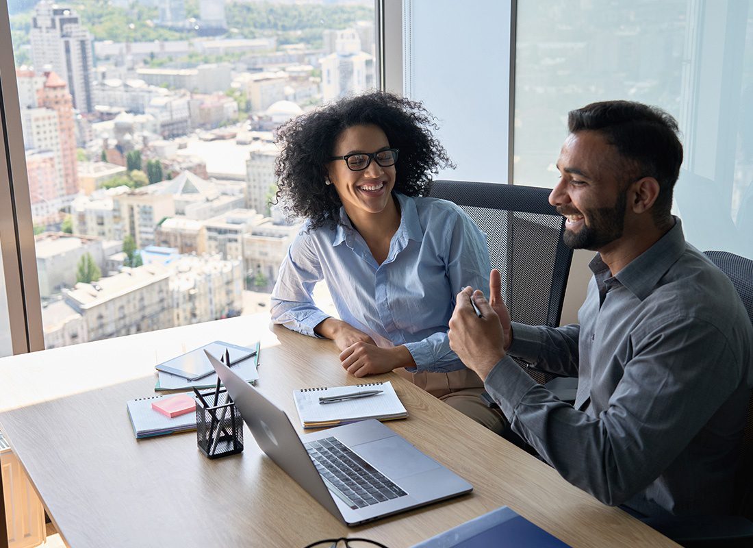 Contact - Two Business Colleagues Sit at a Desk Together While Chatting